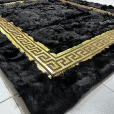 a black and gold area rug on the floor in a room with white tile floors