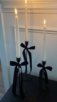 three white candles with black bows on them