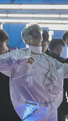 a male in a white shirt and pants with his hands on his hips as if he is dancing