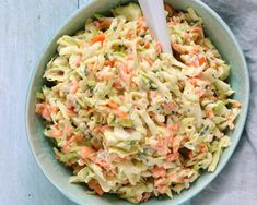 a bowl filled with coleslaw and carrots on top of a blue table