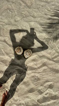 a shadow of a person standing in the sand with their feet up and sandals on