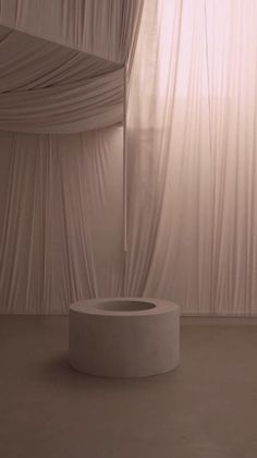 a white round object sitting in front of a curtain