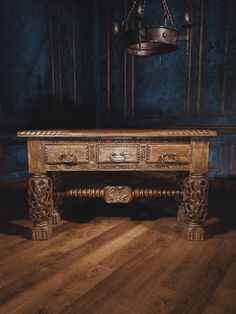 an old wooden table with two drawers on one side and a chandelier hanging from the ceiling