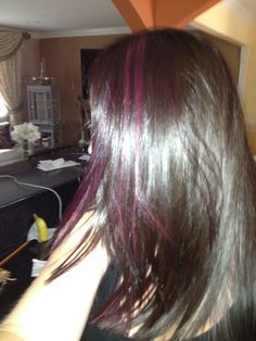 a woman with long dark brown hair and purple streaks on her hair is looking at the mirror