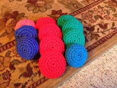 four crocheted balls are laying on the floor in front of a carpeted area