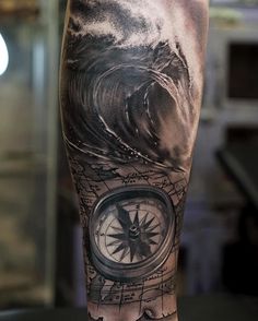 a man's leg with a compass and wave tattoo on it