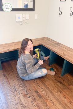 a woman is sitting on the floor with a drill