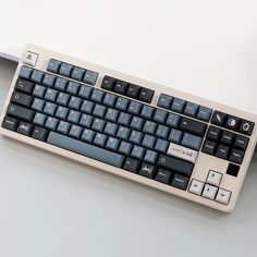 a computer keyboard sitting on top of a white table next to a mouse and pen