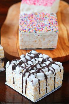 three different desserts sitting on top of a wooden table next to plates with chocolate and sprinkles