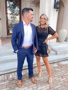 a man and woman standing next to each other in front of a building with stone steps