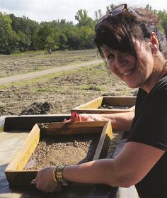 a woman smiles as she places sand in the back of a truck