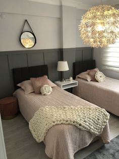 two beds with blankets and pillows in a bedroom next to a lamp on the wall