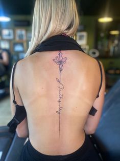 the back of a woman's neck with a flower tattoo on her lower back