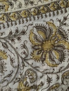 closeup of an ornately designed fabric with gold and brown flowers on white background