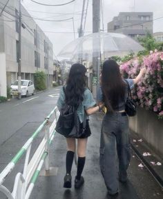 two girls walking down the street in the rain