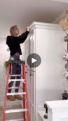 a woman is standing on a ladder and reaching up to reach the top of a cabinet