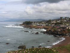 an ocean view with houses on the shore and clouds in the sky