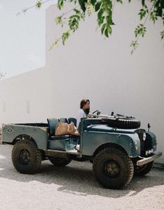 a man sitting on the back of an old blue truck next to a white wall