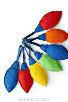 four colorful leaves are hanging from the side of a white wall with blue ribbon around them