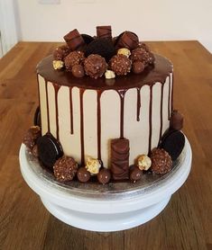 a chocolate cake with white frosting and lots of candies on the top is sitting on a wooden table