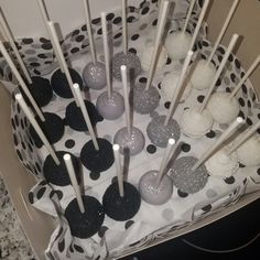 there are many black and white cake pops in the box with polka dots on them