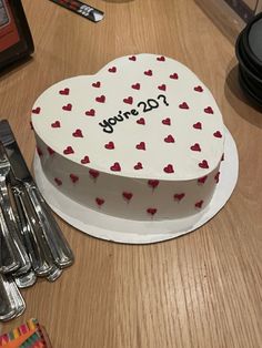 a heart shaped cake sitting on top of a table next to silverware and utensils