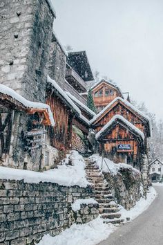 a snow covered street with stairs leading up to some wooden buildings on the side of it