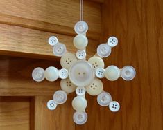 a snowflake made out of buttons hanging from the side of a door