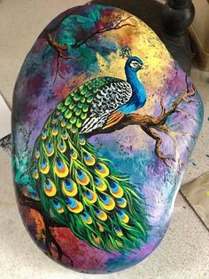 a painted rock with a peacock on it