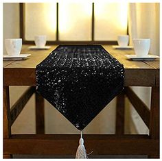 gold sequin table runner with tassels at the end on a wooden table