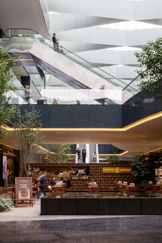 people are walking around in the atrium of a building with an escalator and stairs