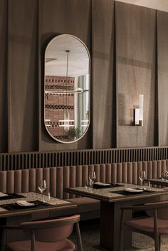 an empty restaurant with tables and chairs in front of a round mirror on the wall