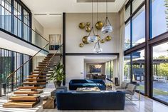 a living room filled with furniture and lots of windows next to a stair leading up to the second floor