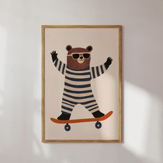 a bear wearing sunglasses riding a skateboard on a white wall with a wooden frame