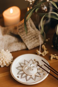 a plate with chopsticks on it next to some flowers and candlelight sticks