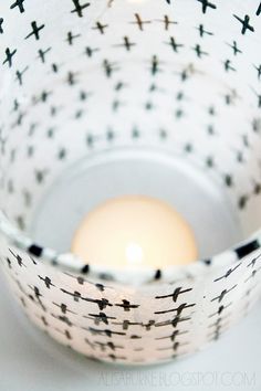 a lit candle in a white bowl with black crosses on it