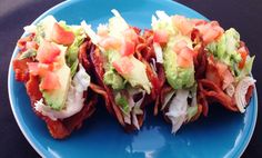 three sandwiches on a blue plate topped with lettuce and tomato slices, avocado and bacon