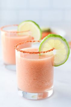 two glasses filled with pink margaritas and lime slices