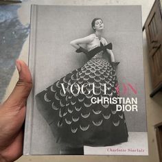 a person holding up a book about christian dior