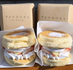 two pandora sandwiches sitting on top of each other in paper wrappers next to boxes