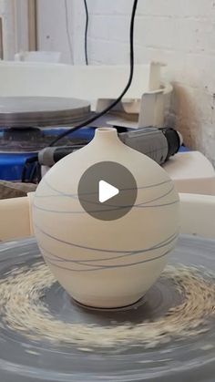 a white vase sitting on top of a table next to some wires and other items