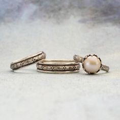 three rings with pearls and diamonds on them