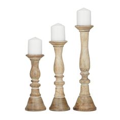 three wooden candlesticks with white candles on them