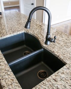 a kitchen sink sitting under a faucet on top of a granite countertop