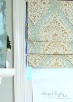 an open window with roman shades on the side and a note attached to the bottom