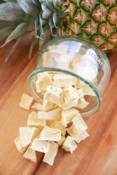 chopped pineapple chunks sitting on top of a wooden table next to a pineapple