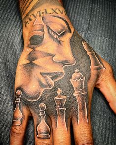 a man's hand with tattoos on it and some chess pieces in the middle