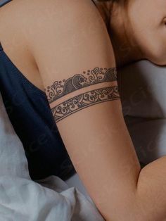 a woman laying in bed with a tattoo on her arm