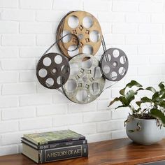 a wooden table topped with a plant next to a wall mounted movie projector film reels