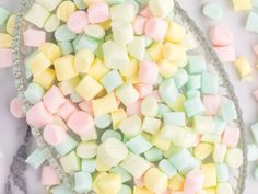 marshmallows in a glass bowl on a marble counter top with other candies